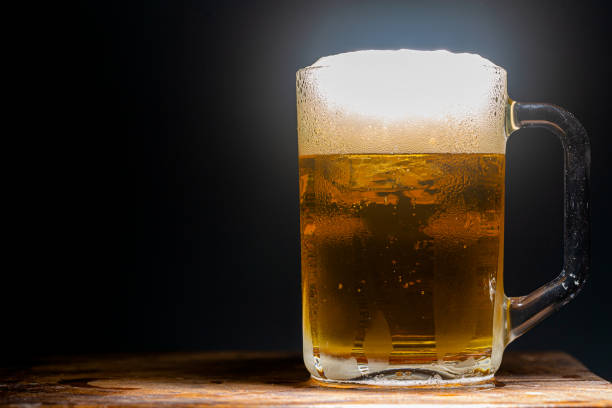 Black background beer glass,Mug of pale beer with foam standing against black background