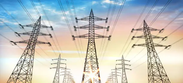 Electrical poles of high voltage in sunrise, high voltage up to yellow sky.