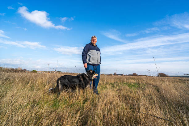 istock Man walking on grassland with border collie 1205564818