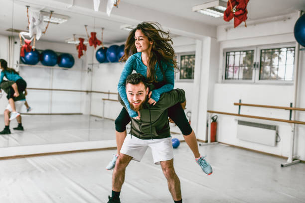 istock Couple Piggyback Ride Exercise In Gym 1205566891