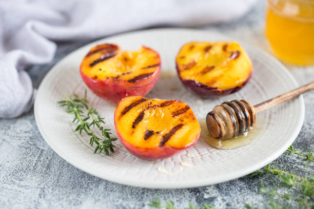Summer dessert: Cooking Ripe grilled peaches with honey stock photo