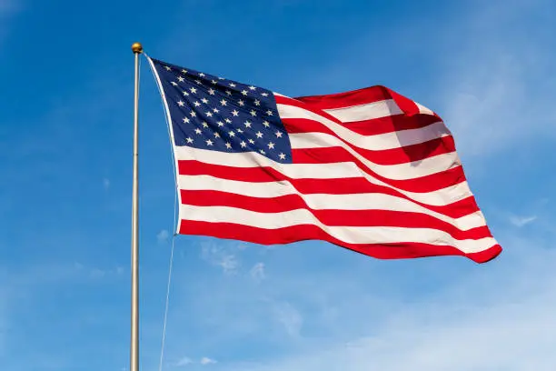 Photo of Vibrant colored American Flag waving in the wind, lit by natural sunlight