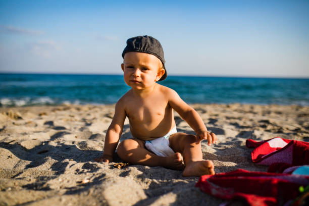istock Little baby boy sitting on the sand 1205568492