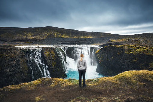 Woman standing in front of beautiful Sigoldufoss waterfalls in Iceland's highlands.