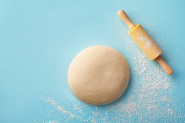istock Dough with flour and rolling pin on blue background top view. Bakery concept. Flat lay. 1205569830