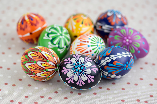 Colorful painted Easter eggs on dotted tablecloth, traditional beautiful Easter still life, bright colors