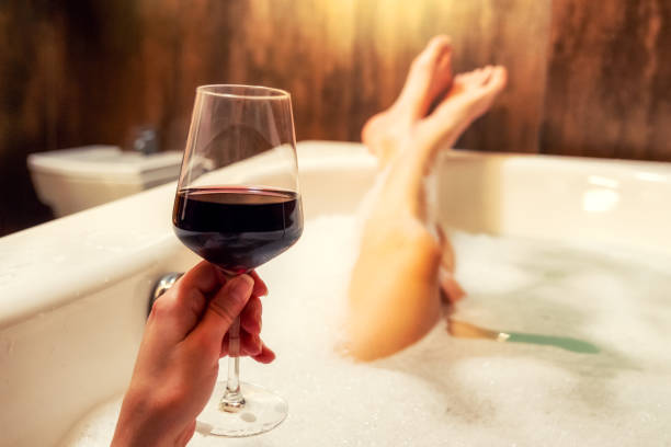 ontspannen in badkuip met glas rode wijn - drinking wine stockfoto's en -beelden