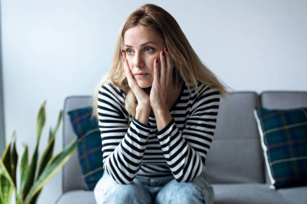 istock Depressed young woman thinking about her problems while sitting on the sofa at home. 1205572466