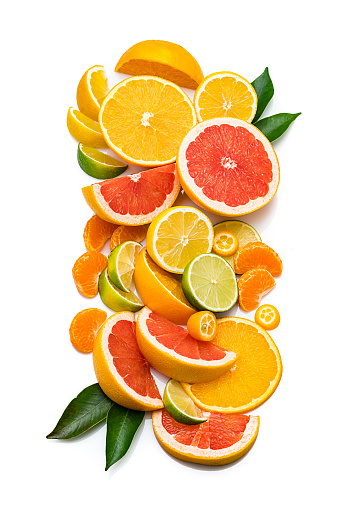 Collection of sliced citrus fruits shot from above on white background. The composition includes slices of grapefruit, orange, lemon, lime, tangerine and kumquat. Some citrus tree leaves complete the composition. High resolution 42Mp studio digital capture taken with Sony A7rii and Sony FE 90mm f2.8 macro G OSS lens