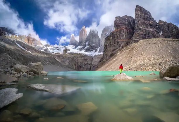 Photo of Hiker in red jacket admiring 3 peaks at Base de las Torres viewpoint in Torres del Paine, Patagonia