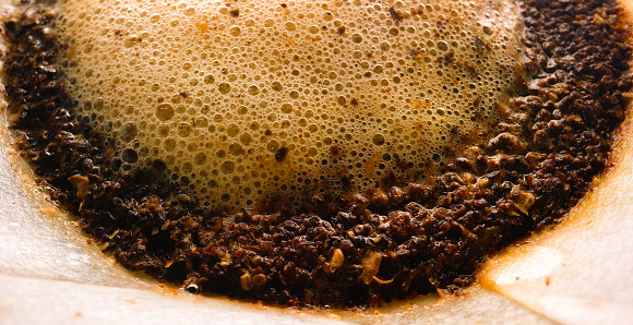 Macro Shot of Hot Water Filtering through Fresh Coffee Grounds in a Paper Filter in a Pour-Over Coffee Maker