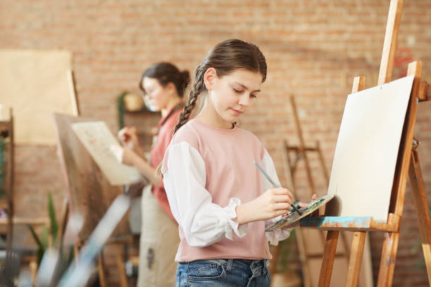 istock Girl painting on easel 1205583656