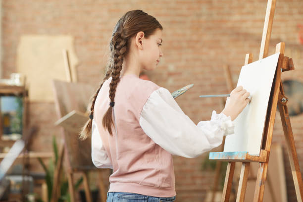 istock Girl painting on easel at art studio 1205583665