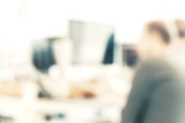istock Man behind a computer at the office, blurred people at the office, meeting at table, Blurred background, officer working on computer at office building, Business background 1205586443