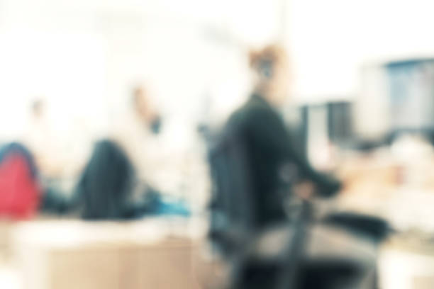 istock Man working on a notebook, blurred people at the office, meeting at table, Blurred background, officer working on computer at office building, Business background 1205586457