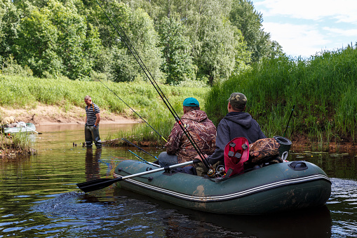 Tuzha, Russia - June 15, 2019: fishermen catch fish on a rubber boat on a forest river. Pizhma River