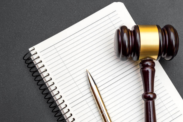 istock Blank notepad with judge gavel and pen on black. 1205588789