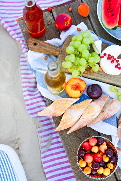 piknik na plaży o zachodzie słońca w stylu boho - beach table peach fruit zdjęcia i obrazy z banku zdjęć