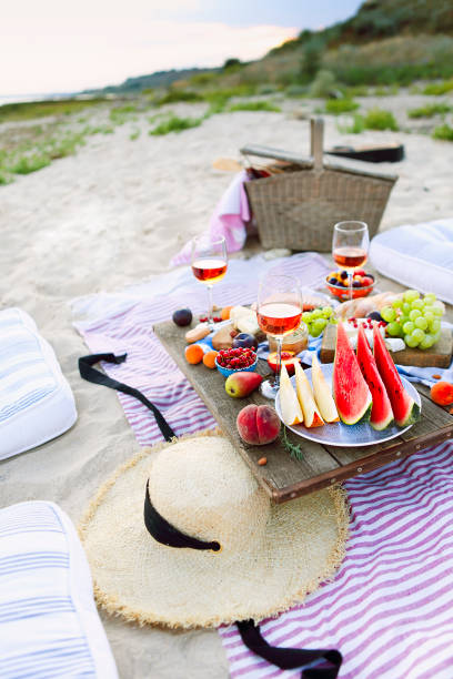 pique-nique sur la plage au coucher du soleil dans le mod�èle de boho - beach table peach fruit photos et images de collection