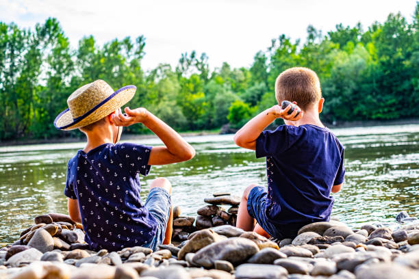 istock Boys enjoying throwing rocks into water 1205593554