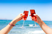Hands of couple enjoying glasses of champagne on tropical beach