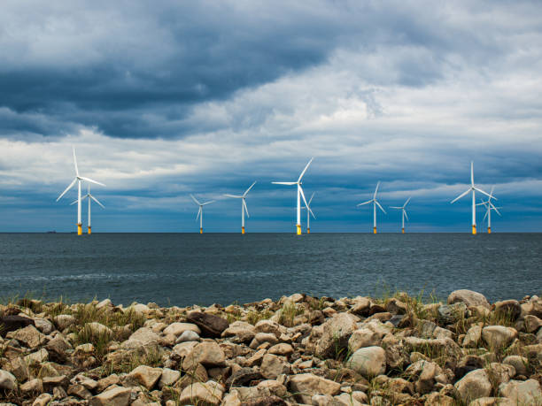 Offshore Wind Farm Wind turbines off the shore of South Gare, UK with rocky beach in foreground. offshore wind farm stock pictures, royalty-free photos & images