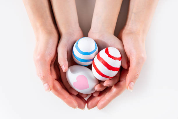 istock Mother and her child hands holding painting Easter eggs 1205595308
