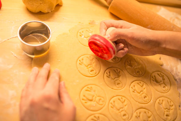 frauen hand machen traditionelle weihnachtsplätzchen. rohteig und cutter für urlaubskekse auf dem tisch. bereiten sie die lebkuchen. reindeer teig stempel. - cookie heart shape shortbread christmas stock-fotos und bilder