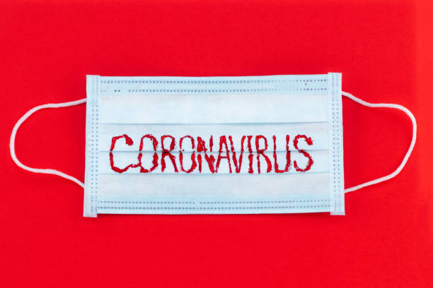 istock Novel coronavirus - 2019-nCoV, COVID-19 concept. Surgical mask protective mask with CORONAVIRUS text. COVID-19 outbreak. Red background 1205596537
