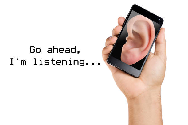 istock hand holding smartphone with human ear listening displayed on it isolated. Privacy concecpt 1205598927
