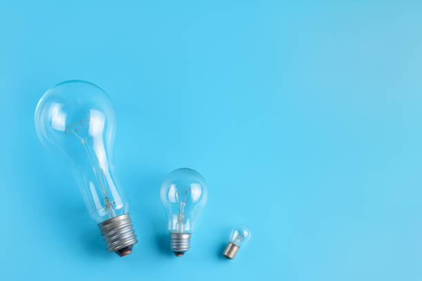 istock Big, normal and tiny classic incandescent lamps on a blue background. 1205601418