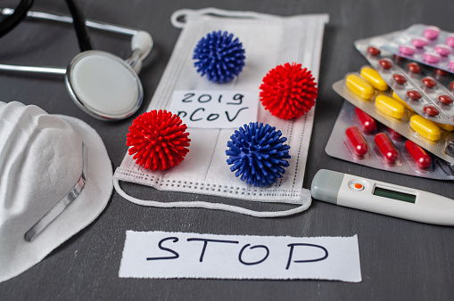 Model of a coronavirus strain from China. Outbreak of respiratory syndrome and the new 2019-nCoV coronavirus on a gray background. Stethoscope, thermometer, surgical mask and pills.