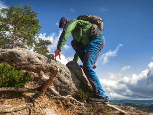 istock Man climbing steep mountain slope. Sunny  windy day 1205601483