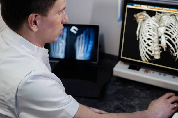 istock in medical laboratory patient undergoes MRI or CT scan process under Supervision of Radiologist in Control Room, He Watches Procedure and Monitors skeleton and ribs of the patient 1205602719