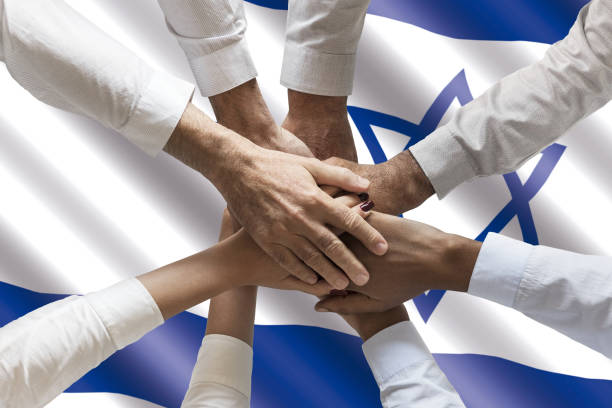 Stack of human hands over waving Israeli flag