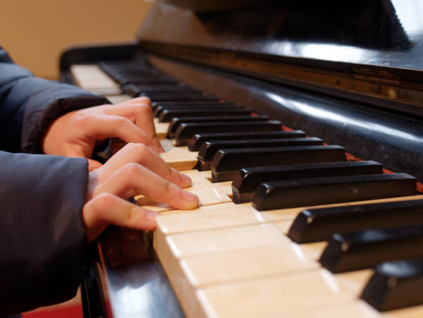 istock kid or child hands playing piano closeup 1205603662