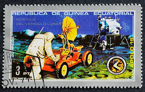 Photograph of a canceled postage stamp from the Republica De Guinea celebrating the Apollo 15 Space Mission. Shot on black background.