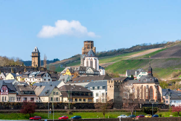 Crusing up the Rhine River on a River Boat we pass Oberwesel which is a town on the Middle Rhine in the Rhein-Hunsrück-Kreis (district) in Rhineland-Palatinate, Germany where we see a Church with a Clock Tower, and a Grape Orchard on the Hillside beyond. enloquecando el río rin en un barco fluvial pasamos oberwesel, que es una ciudad en el rin medio en el rhein-hunsrack-kreis (distrito) en renania-palatinado, alemania, donde vemos una iglesia con una torre del reloj, y un huerto de uvas en la ladera más