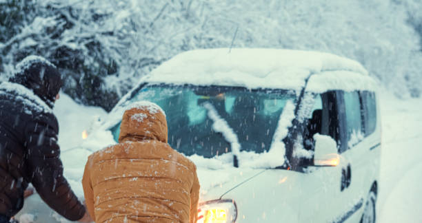 auto blieb im schnee auf der straße stecken, menschen, die versuchen, es auszuziehen. - manually stock-fotos und bilder