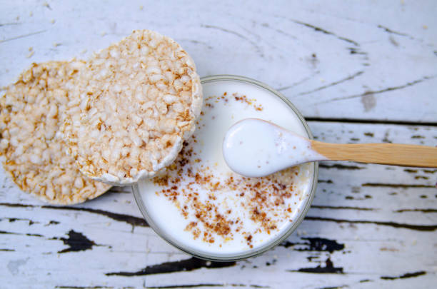 istock Rice rounded cookie bread alternative and kefir yogurt with linen milled seed, served in glass bowl with wooden spoon on white rustic board 1205608514