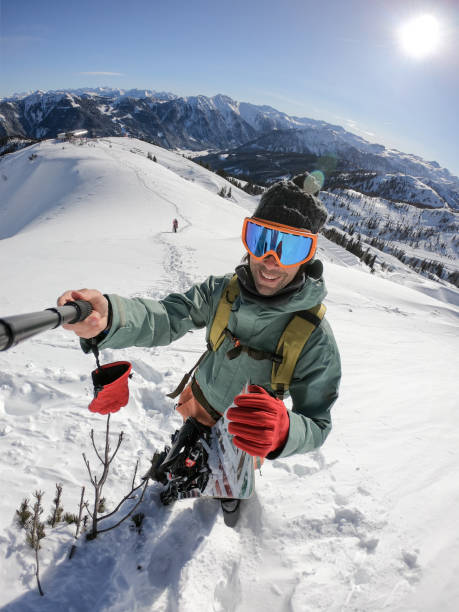 Snowboarder taking selfie on top of the mountain stock photo