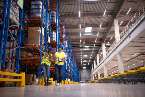 istock Shot of two workers walking through large warehouse center, observing racks with goods and planing distribution to the market. Storehouse department organization. 1205610328