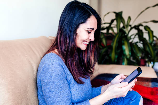 istock young woman sitting at cozy home sofa and using modern smart phone device, female hands typing text message. social networking concept 1205613018