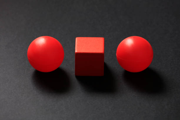Red tennis ball and cube shape on a black background