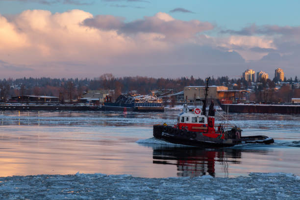 istock Industrial Tugboat pulling a load in Fraser River during a colorful winter sunset with ice in the water. 1205617126
