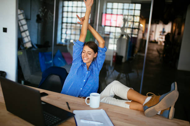 istock Happy woman stretching in front of desk at work 1205618603