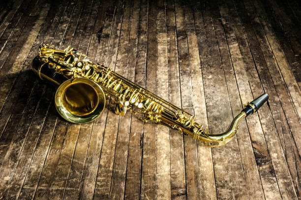 le saxophone jaune d’instrument de musique de jazz se trouve sur une scène brune en bois - classical music music musical instrument brown photos et images de collection