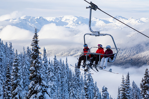 Whistler, British Columbia, Canada - January 9, 2020: People going up the mountain on a Chairlift during a vibrant and sunny winter day.