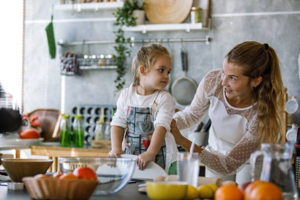 istock Mother tying a bow on her little daughter's apron before preparing food 1205627189