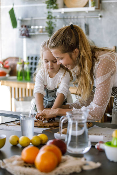 matka i jej córeczka wycinają ciasteczka razem - vegan food cheerful vertical indoors zdjęcia i obrazy z banku zdjęć